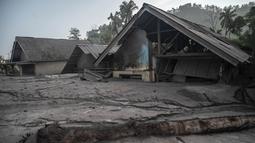 Rumah-rumah yang rusak terendam lumpur setelah letusan gunung berapi oleh Gunung Semeru di desa Kajar Kuning di Lumajang (5/12/2022). Gunung Semeru meletus pada tanggal 4 Desember memuntahkan awan abu panas setinggi satu mil dan sungai lava di sisinya sambil memicu evakuasi hampir 2.000 orang tepat satu tahun setelah letusan besar terakhirnya menewaskan puluhan orang. (AFP/Juni Kriswanto)