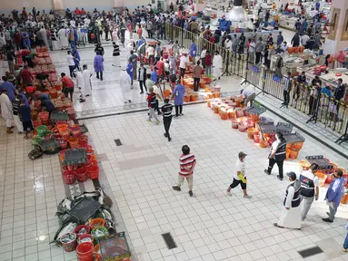 Orang-orang berbelanja selama pelelangan di pasar ikan di Kuwait City (8/8/2021). Pelelangan dibuka kembali di negara itu setelah enam bulan ditutup di tengah pandemi virus corona. (AFP/ Yasser Al-Zayyat)