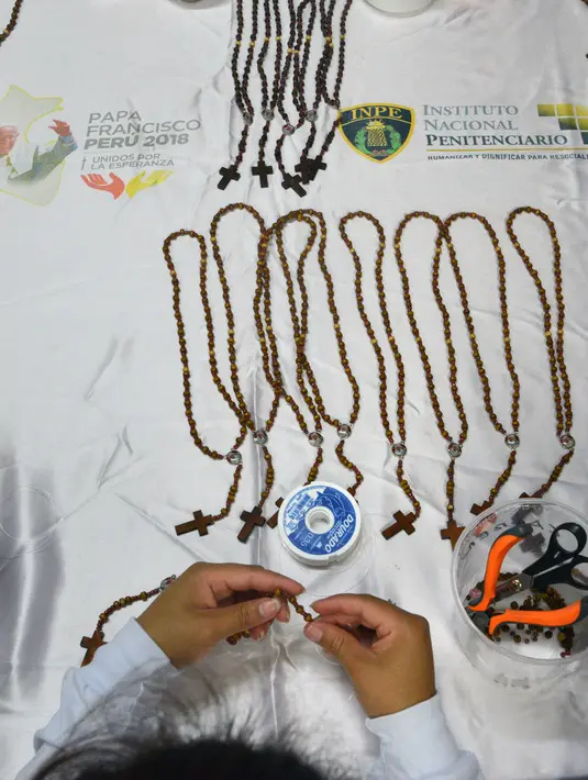 Seorang narapidana di penjara Wanita Virgen de Fatima menyelesaikan rosario kayu buatan tangan di Lima, Peru (12/1). Rosario tersebut dibuat untuk menyambut kedatangan Paus Fransiskus ke Peru pada tanggal 18-21 Januari. (AFP Photo/Cris Bouroncle)