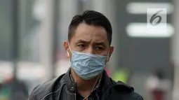 Pejalan kaki mengenakan masker saat berjalan di Jakarta, Kamis (4/7/2019). Organisasi lingkungan Greenpeace menyatakan kualitas udara Jakarta saat ini terpantau sangat tidak sehat dengan angka 165 AQI atau Indeks Kualitas Udara. (merdeka.com/Imam Buhori)