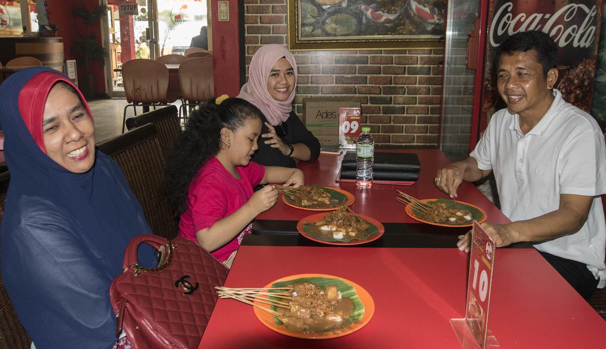 Pelatih Mitra Kukar, Jafri Sastra, didampingi istri dan kedua anaknya makan sate padang di kawasan Jakarta Selatan, Sabtu (23/1/2016). (Bola.cm/Vitalis Yogi Trisna)