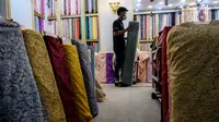 Pekerja menata bahan kain dagangan di Pasar Tanah Abang, Jakarta, Kamis (1/4/2021). Kemenperin ingin meningkatkan daya saing industri Tekstil dan Produk Tekstil (TPT) nasional, salah satunya dengan berupaya mengurangi ketergantungan terhadap bahan baku tekstil impor. (Liputan6.com/Johan Tallo)
