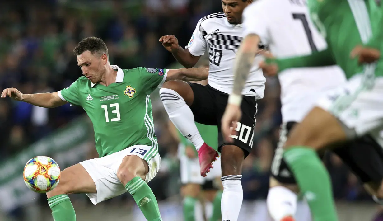 Gelandang Irlandia Utara, Corry Evans, berebut bola dengan gelandang Jerman, Serge Gnabry, pada laga Kualifikasi Piala Eropa 2020 di Windsor Park, Belfast, Senin (9/9). Irlandia Utara kalah 0-2 dari Jerman. (AFP/Paul Faith)