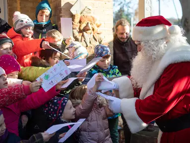 Seorang pria berpakaian Santa Claus disambut anak-anak selama pembukaan kantor surat Natal yang paling terkenal di Himmelpfort, Kamis (14/11/2019). Seperti tahun-tahun sebelumnya pada Natal kali ini Santa Klaus di Jerman sangat sibuk. (Soeren Stache/dpa via AP)