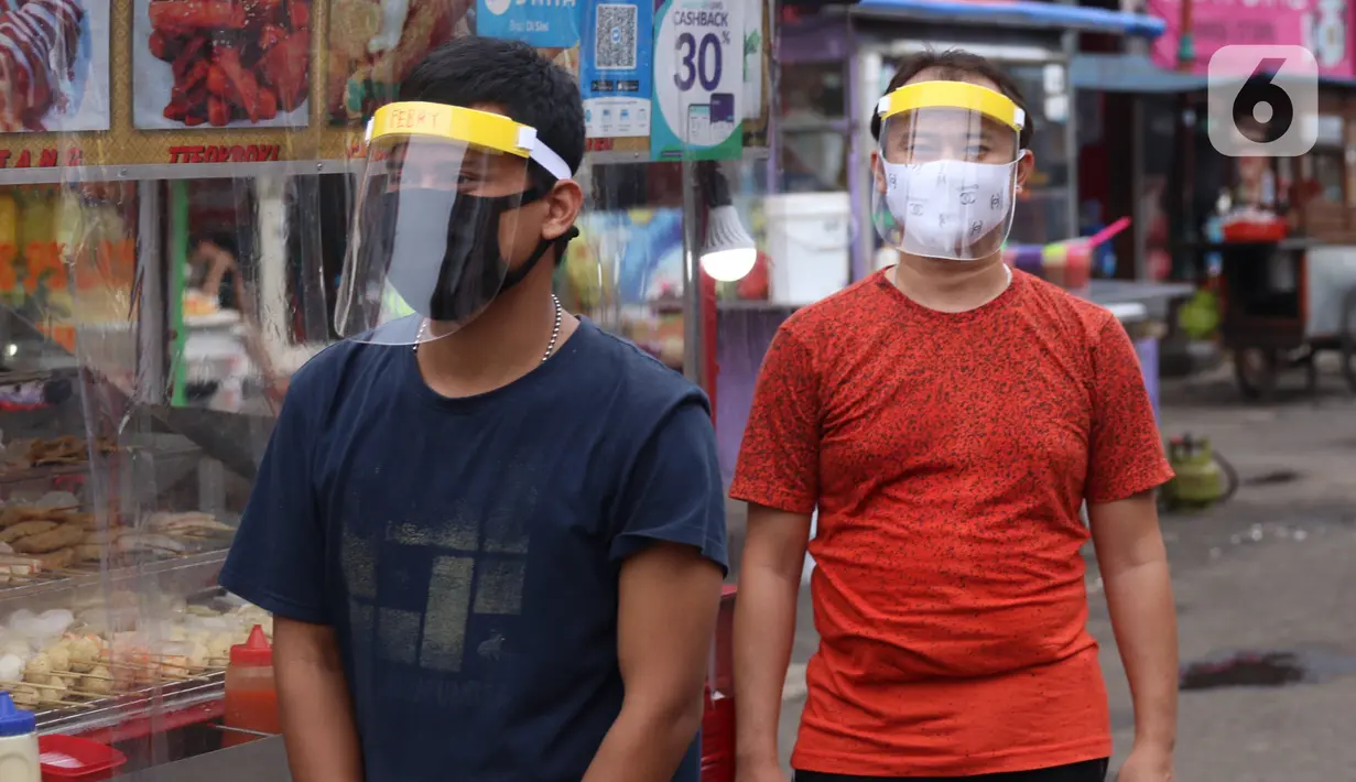 Pedagang mengenakan face sheild atau pelindung wajah saat berjualan di Tangerang, Banten, Rabu (13/5/2020). Penggunaan pelindung wajah tersebut dilakukan untuk mencegah risiko penularan virus corona COVID-19 pada saat berdagang. (Liputan6.com/Angga Yuniar)