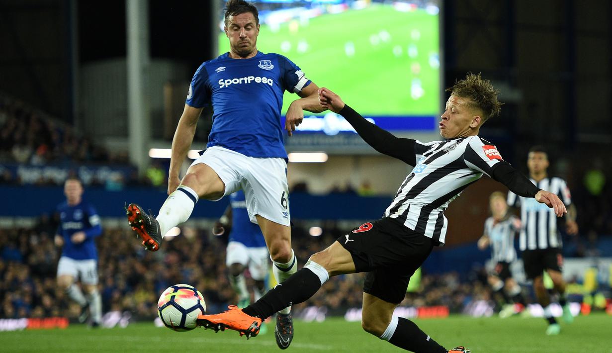 Pemain Newcastle United, Dwight Gayle (kanan) mencoba menjangkau bola dari kejaran pemain Everton, Phil Jagielka pada lanjutan Premier League di Goodison Park, Liverpool,(23/4/2018). Everton menang 1-0. (AFP/Oli Scarff)