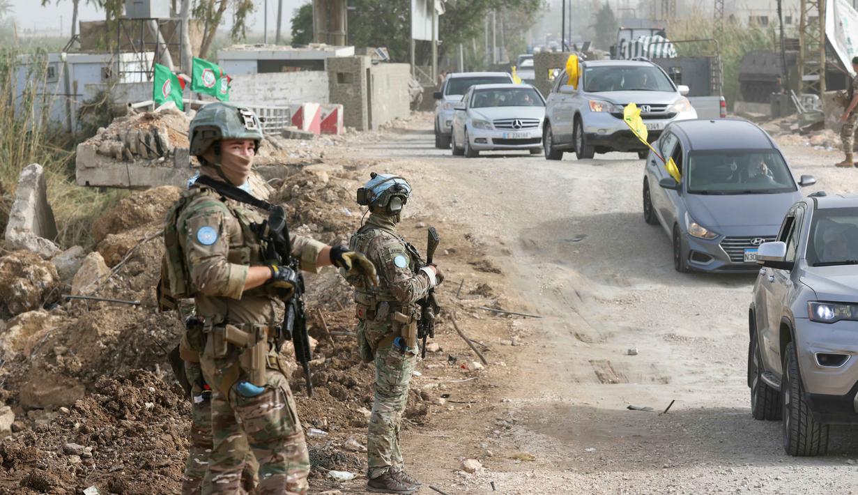 Kontingen Prancis dari Pasukan Sementara Perserikatan Bangsa-Bangsa (PBB) di Lebanon (UNIFIL) berpatroli, sementara warga yang mengungsi sambil mengibarkan bendera Hizbullah kembali ke rumah mereka melalui jalan darurat yang dibangun di lokasi jembatan Qasmieh yang hancur akibat serangan Israel, di wilayah Al-Qasmiyeh, Lebanon Selatan, pada Sabtu 18 April 2026. Israel dan Lebanon resmi menyepakati gencatan senjata selama 10 hari. (MAHMOUD ZAYYAT/AFP)