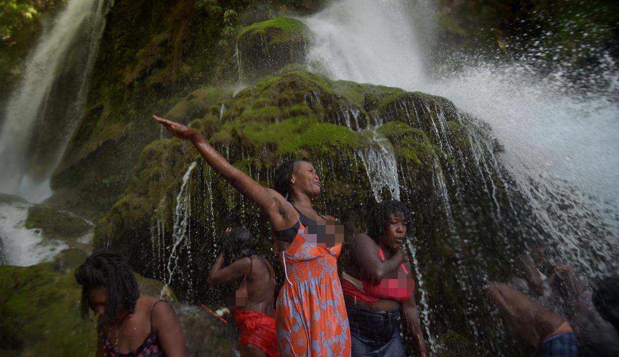 Sejumlah peziarah mandi di bawah air terjun di Saut d' Eau, Haiti (15/7). Mereka merupakan penganut Kristen Haiti yang masih percaya Voodoo. (AFP Photo/Hektor Retamal)