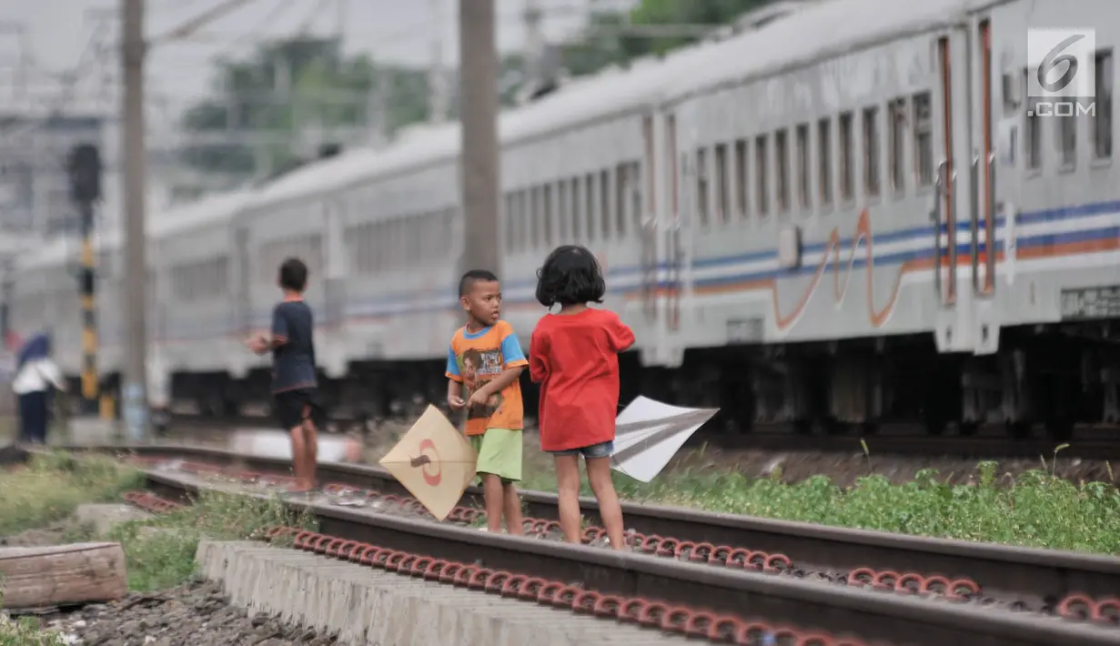 Anak-anak bermain layang-layang di rel kereta api kawasan Jakarta Timur, Kamis (3/1). Minimnya lahan terbuka hijau memaksa anak-anak setempat memilih kawasan rel kereta api sebagai lokasi bermain. (Merdeka.com/Iqbal Nugroho)