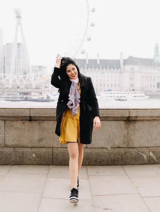 Gaya Ochi saat tengah berlibur di London, Inggris ini pun terlihat kasual. Dirinya hanya mengenakan dress berwarna kuning dengan sneakers hitam senada dengan coat yang dikenakan. (Liputan6.com/IG/@ochi24)