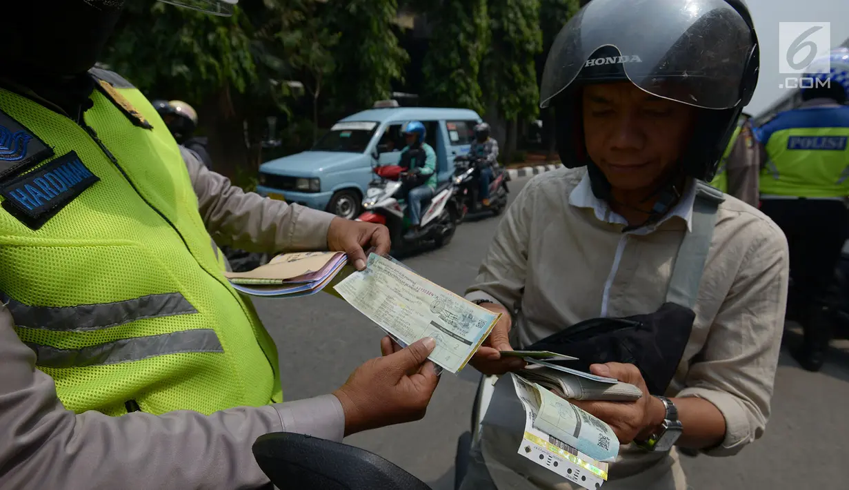 Polisi lalu lintas memeriksa kelengkapan surat pengendara saat razia Operasi Patuh Jaya 2019 di kawasan Kebon Nanas, Jakarta, Kamis (29/8/2019). Operasi ini diharapkan dapat meningkatkan kepatuhan dan ketertiban dalam berlalu lintas serta mengurangi angka kecelakaan. (merdeka.com/Imam Buhori)