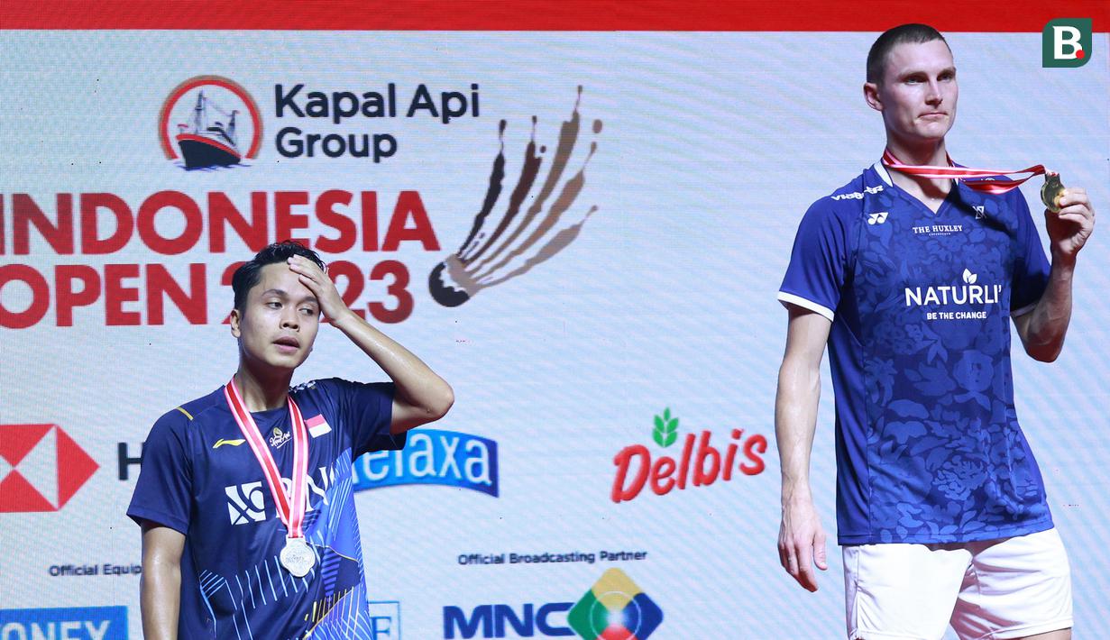 Ekspresi tunggal putra Indonesia, Anthony Ginting (kiri), di atas podium bersama Viktor Axelsen, setelah laga final Indonesia Open 2023 di Istora Gelora Bung Karno, Jakarta, Minggu (18/6/2023). (Bola.com/M Iqbal Ichsan)