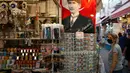 Poster pendiri Turki modern Mustafa Kemal Ataturk terlihat di sebuah toko, ketika turis yang mengenakan masker melintas di kota Ayvalik, Laut Aegea, Rabu (9/9/2020). Turki telah mewajibkan penggunaan masker di semua lokasi selain di rumah, menyusul lonjakan kasus COVID-19. (AP Photo/Emrah Gurel)