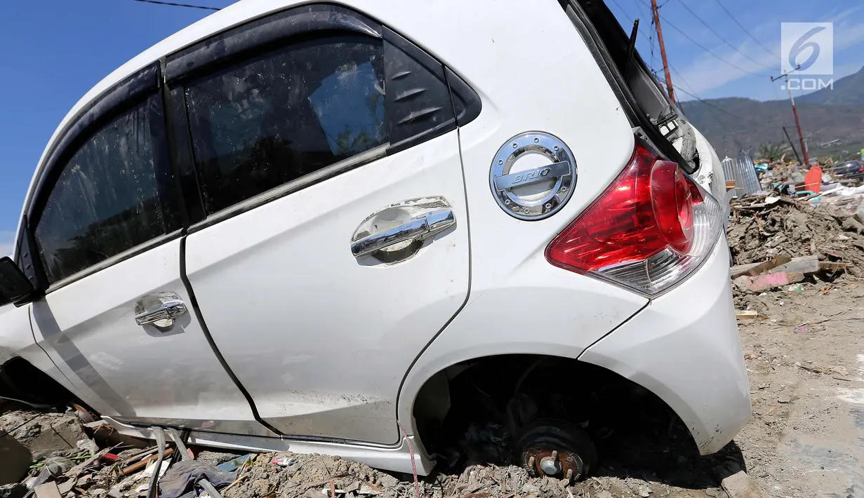 Sebuah mobil Honda Brio menjadi incaran jarahan korban gempa dan tsunami di Palu Grand Mal, Palu, Jumat (5/10). Warga korban gempa bumi mengambil ban dan interior mobil. (Liputan6.com/Fery Pradolo)