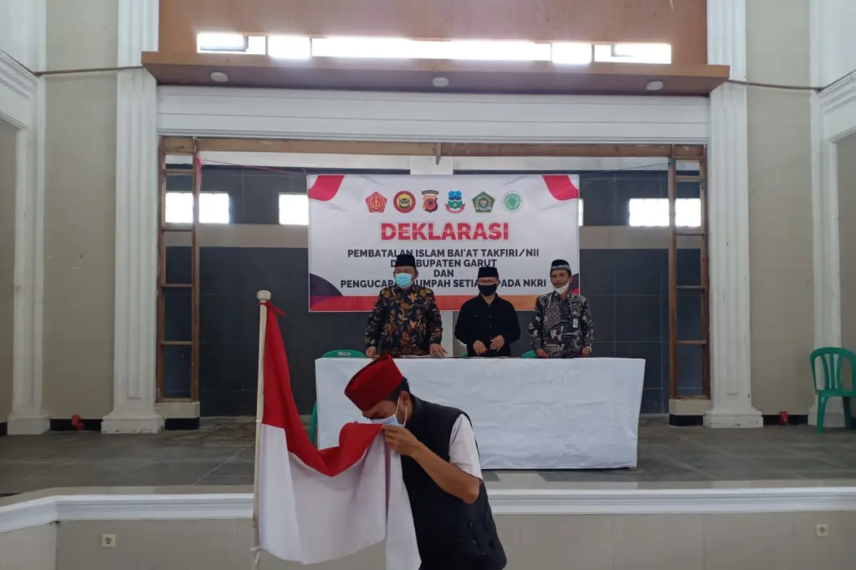 Salah seorang warga bekas anggota NII tengah mencium bendera merah putih sebagai bukti ikrar kembali kepada pangkusan NKRI. (Liputan6.com/Jayadi Supriadin)
