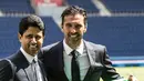 Kiper anyar PSG, Gianluigi Buffon berpose bersama Ketua klub dan CEO Paris Saint-Germain, Nasser Al Khelaifi sambil memegang jersey PSG saat resmi diperkenalkan sebagai pemain baru di stadion Parc des Princes, Paris, Senin (9/7). (AP/Jean-Francois Badias)