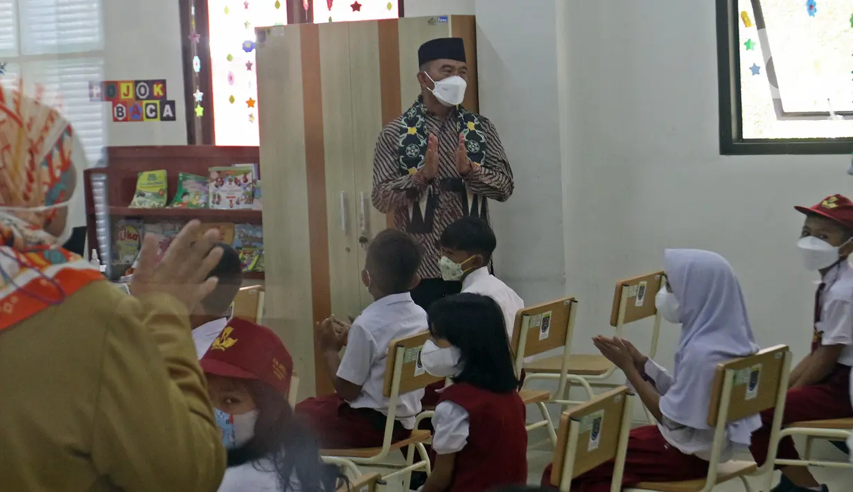 Menko PMK Muhadjir Effendy menyapa para siswa saat meninjau vaksinasi COVID-19 di SDN 01 Depok, Depok, Jawa Barat, Selasa (14/12/2021). Kunjungan tersebut untuk melihat persiapan vaksinasi COVID-19 anak usia 6-11 tahun yang dilaksanakan mulai hari ini. (Liputan6.com/Herman Zakharia)