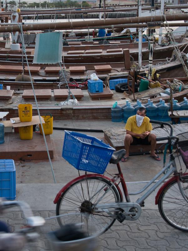 Seorang petugas keamanan bersepeda melewati nelayan di kawasan Deira, Dubai, Uni Emirat Arab, Minggu (5/4/2020). Hingga 4 April 2020, Badan Kesehatan Uni Emirat Arab mencatat ada 1.505 kasus virus corona COVID-19, sebanyak 16 orang di antaranya meninggal. (AP Photo/Jon Gambrell)