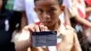 Seorang anak memperlihatkan Kartu Indonesia Pintar di Penjaringan, Jakarta, Rabu (13/5). Pembagian KIS, KIP dan KKS itu untuk meningkatkan kualitas hidup, kesehatan serta pendidikan bagi masyarakat.(Liputan6.com/Faizal Fanani)
