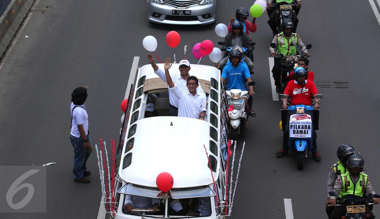 Pasangan Anis Baswesan dan Sandiaga Uno menyapa warga saat berada di mobil karnaval di Thamrin, Jakarta, Sabtu (29/10). Karnaval tersebut merupakan bentuk kampanye damai untuk pemilihan Gubernur DKI Jakarta. (Liputan6.com/Angga Yuniar)