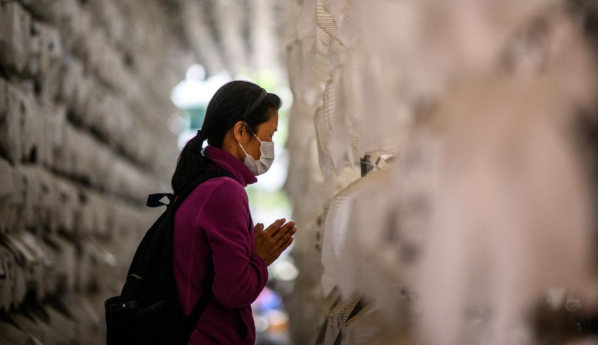 <p>Seorang wanita berdoa di depan lentera teratai putih dengan nama dan doa tertulis pada atasnya setelah kebaktian untuk merayakan ulang tahun Buddha di Kuil Jogye, Seoul, Korea Selatan, Minggu (8/5/2022). (ANTHONY WALLACE/AFP)</p>