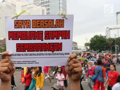 Seorang warga menunjukkan tulisan Saya Bersalah Membuang Sampah Sembarangan saat CFD di Jakarta, Minggu (28/1). Petugas Dari Suku Dinas Lingkungan Hidup DKI Jakarta melakukan OTT bagi para warga yang kedapatan membuang sampah. (Liputan6.com/Angga Yuniar)