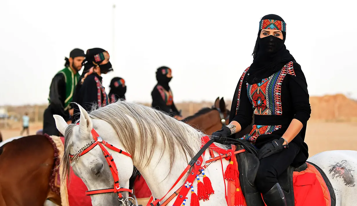 Perempuan Arab berpose saat menunggangi kuda dalam Festival Souk Okaz 2019 di Kota Taif, Arab Saudi, Rabu (7/8/2019). Tahun ini merupakan pertama kalinya perempuan diizinkan untuk berpartisipasi dalam Festival Souq Okaz 2019. (AMER HILABI/AFP)