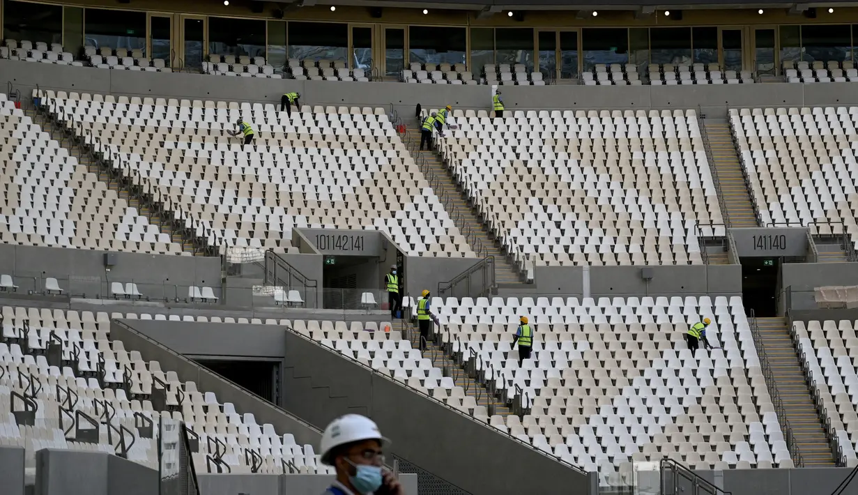 Pekerja membersihkan tribun Lusail Stadium di Lusail, Qatar, 28 Maret 2022. Stadion berkapasitas 80 ribu penonton yang terletak di pinggiran Ibu Kota Doha ini akan menjadi tuan rumah final Piala Dunia 2022 pada bulan Desember mendatang. (GABRIEL BOUYS/AFP)