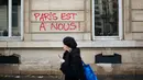 Seorang wanita berjalan melewati grafiti bertuliskan 'Paris adalah milik kita' dekat Arc de Triomphe, Paris, Prancis, Minggu (2/12). Pemrotes kenaikan pajak bahan bakar menandai Arc de Triomphe dengan grafiti berbagai warna. (AP Photo/Kamil Zihnioglu)