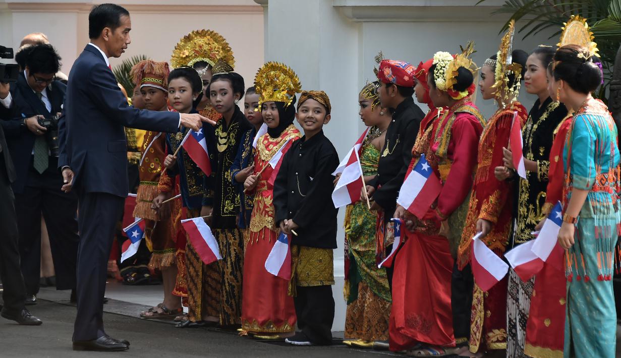 Presiden Jokowi menyapa anak-anak berpakaian tradisional Nusantara saat menunggu kedatangan Presiden Republik Chile, Michelle Bachelet di Istana Kepresidenan, Jakarta, Jumat (12/5). Kedatangan Bachelet disambut dengan parade kenegaraan. (Bay ISMOYO/AFP)