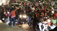Seorang pria mengatur arus lalu lintas pemudik bersepeda motor di ruas Kalimalang, Bekasi, Kamis (22/6). Pada malam hari peningkatan kendaraan pemudik terutama yang menggunakan roda dua jauh lebih tinggi dibanding siang hari. (Liputan6.com/Angga Yuniar)
