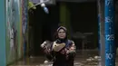 Warga melintasi banjir di kawasan Kebon Pala, Kampung Melayu, Jakarta Timur, Sabtu (16/7/2022). Meskipun ketinggian air sudah mencapai paha orang dewasa, warga setempat belum memutuskan untuk mengungsi. (merdeka.com/Imam Buhori)