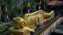 Prosesi memandikan dilakukan dengan menyiram semua bagian patung Buddha tidur dengan air yang berisi bunga. Selanjutnya, permukaan patung dibersihkan menggunakan sikat. (JUNI KRISWANTO/AFP)