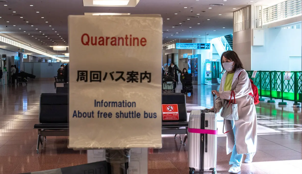 Seorang penumpang berjalan dengan kopernya di aula kedatangan di Bandara Internasional Haneda Tokyo, Jumat (18/2/2022). Pemerintah Jepang mengumumkan rencana untuk melonggarkan aturan perbatasan virus bagi pekerja dan pelajar. (AFP/Philip Fong)