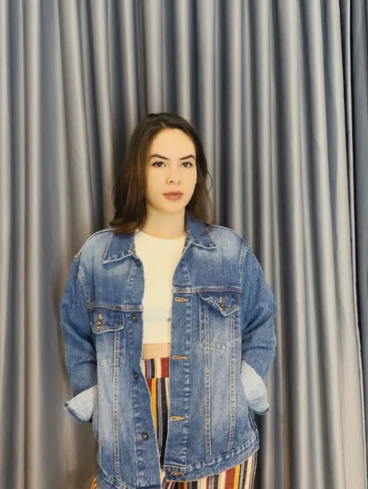 Bahkan denim oversize pun tetap cocok dikenakannya. Dipadukan dengan crop tee putih dan bawahan motif bergaris, gadis 19 tahun ini tampil modis banget. (Liputan6.com/IG/@steffizamoraaa)