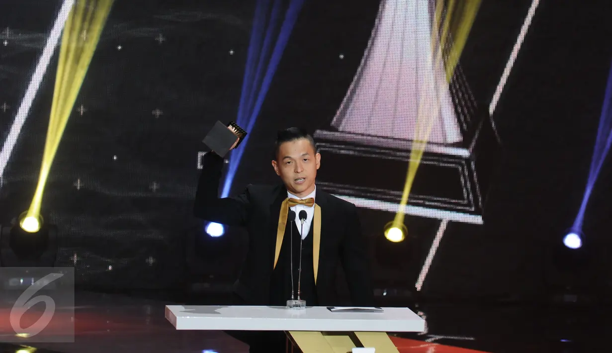 Ernest Prakasa mengangkat piala usai dinobatkan sebagai Penulis Skenario Terbaik dari film Cek Toko Sebelah pada Indonesian Box Office Movie Awards 2017 di Studio 6 Emtek City, Jakarta, Rabu (29/3). (Liputan6.com/Helmi Fithriansyah)