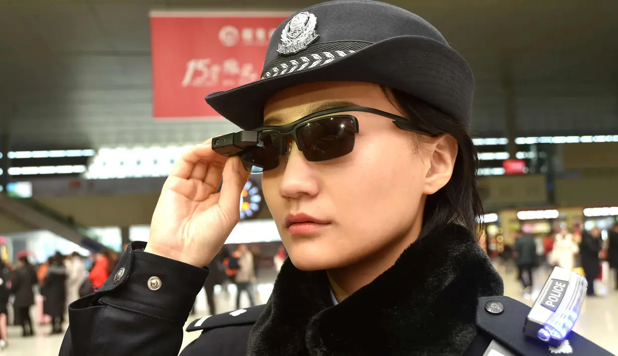 Petugas polisi China mengenakan kacamata dengan sistem pengenalan wajah di Stasiun Kereta Zhengzhou East, China (5/2). Teknologi dalam kacamata ini juga bisa memberitahu para polisi soal terduga pelaku kejahatan yang melarikan diri. (AFP Photo/China Out)