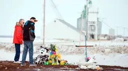 Orang-orang memberi penghormatan di lokasi kecelakaan bus di Provinsi Saskatchewan, Kanada (9/4). Sebelumnya sebuah bus yang membawa tim hoki Humboldt Broncos junior menabrak truk dan menewaskan 14 orang. (Jonathan Hayward/The Canadian Press via AP)