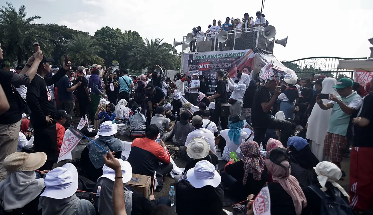 Massa #2019GantiPresiden mendengarkan orator menyampaian pesan dari atas mobil komando saat deklarasi akbar di Monas, Jakarta, Minggu (6/5). Massa menyerukan pergantian presiden secara konstitusional melalui Pilpres 2019. (Merdeka.com/Iqbal Nugroho)