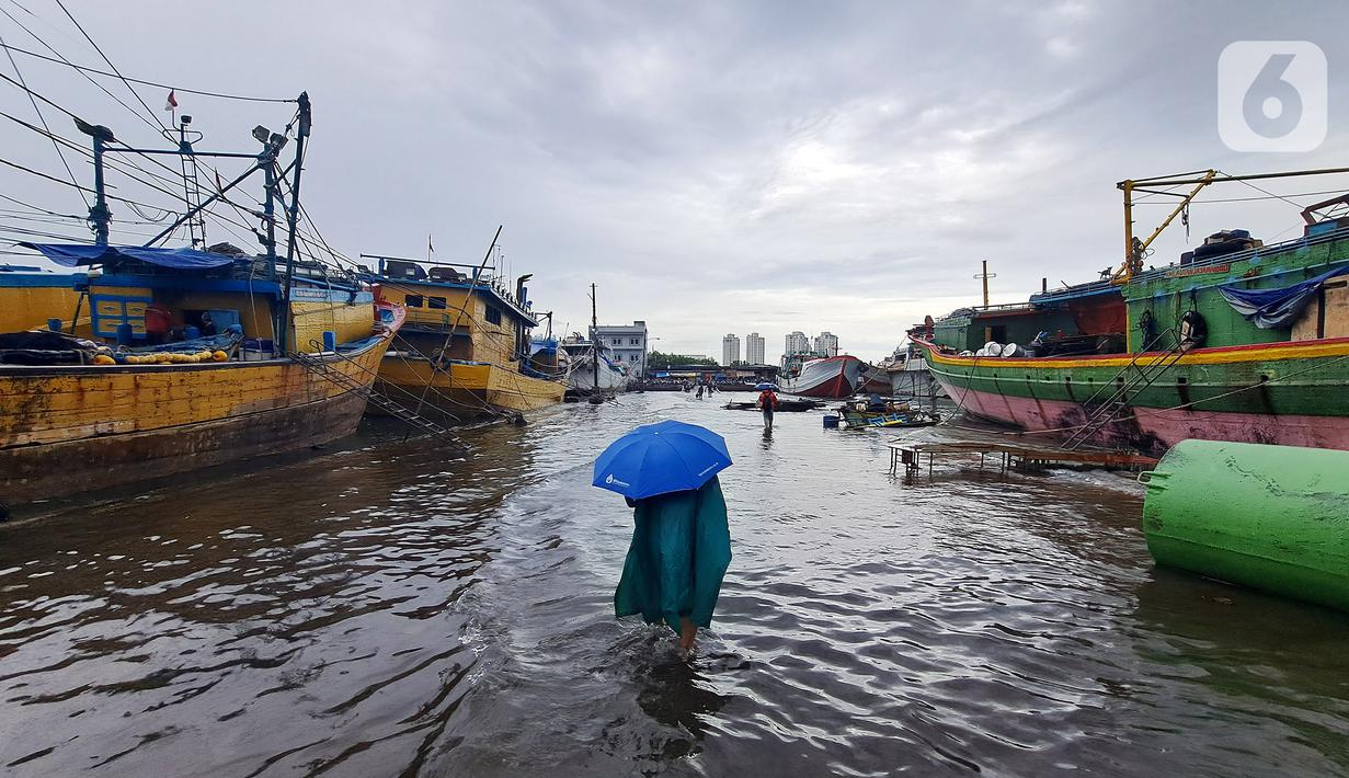Nelayan melintasi banjir rob saat cuaca ekstrem di Pelabuhan Muara Baru, Penjaringan, Jakarta Utara, Rabu (28/12/2022). Banjir ROB, hujan deras dan  cuaca buruk melanda kawasan Pelabuhan Muara Baru saat siang menjelang sore hari. (Liputan6.com/Johan Tallo)