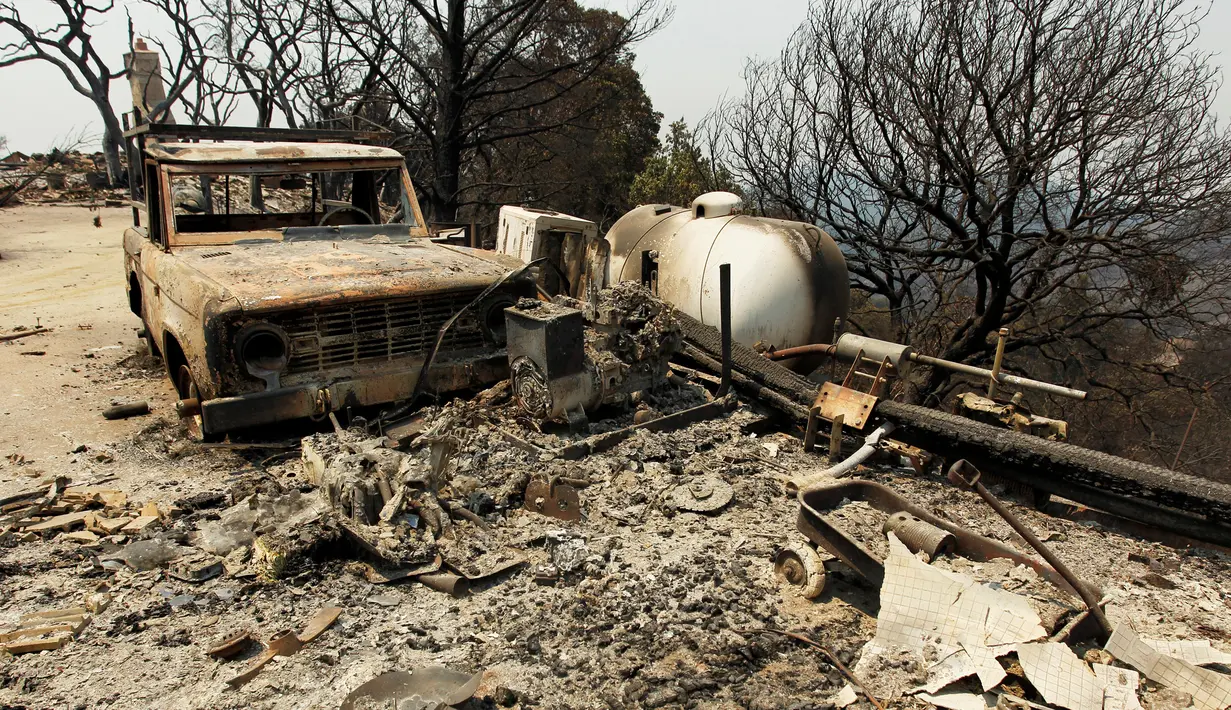 Sebuah mobil hangus terbakar yang tidak sempat diselamatkan pemiliknya akibat kebakaran hutandi kawasan Palo Colorado, Big Sur, California, AS, (31/7). Setidaknya 300 telah dievakuasi akibat musibah tersebut. (REUTERS/Michael Fiala)