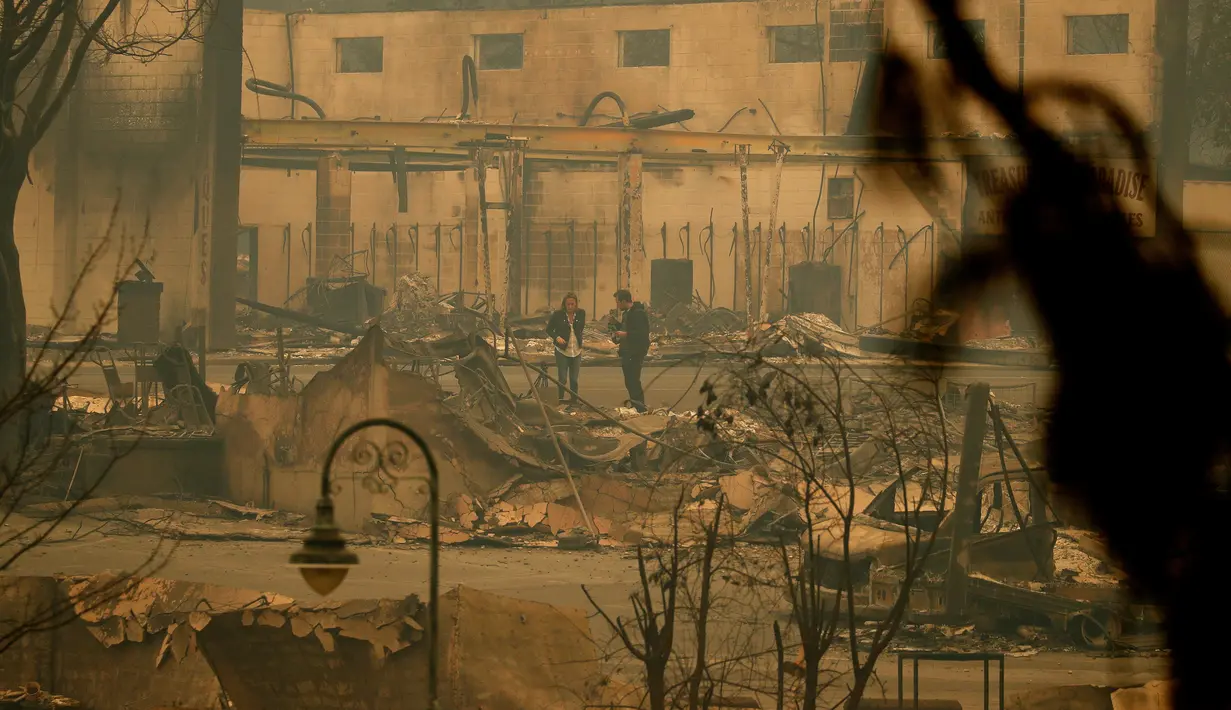 Wartawan melihat-lihat dampak kerusakan usai kebakaran melanda Kota Paradise, California, AS, Selasa (13/11). Sekitar 9.000 petugas pemadam kebakaran saat ini berjuang melawan kebakaran hutan di utara dan selatan California. (AP Photo/John Locher, File)