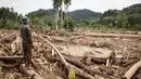 Seorang pria melihat kerusakan yang disebabkan oleh banjir yang membawa sisa-sisa pembalakan liar di Pelangai Gadang, Sumatera Barat, pada Sabtu 15 Maret 2025. (REZAN SOLEH/AFP)