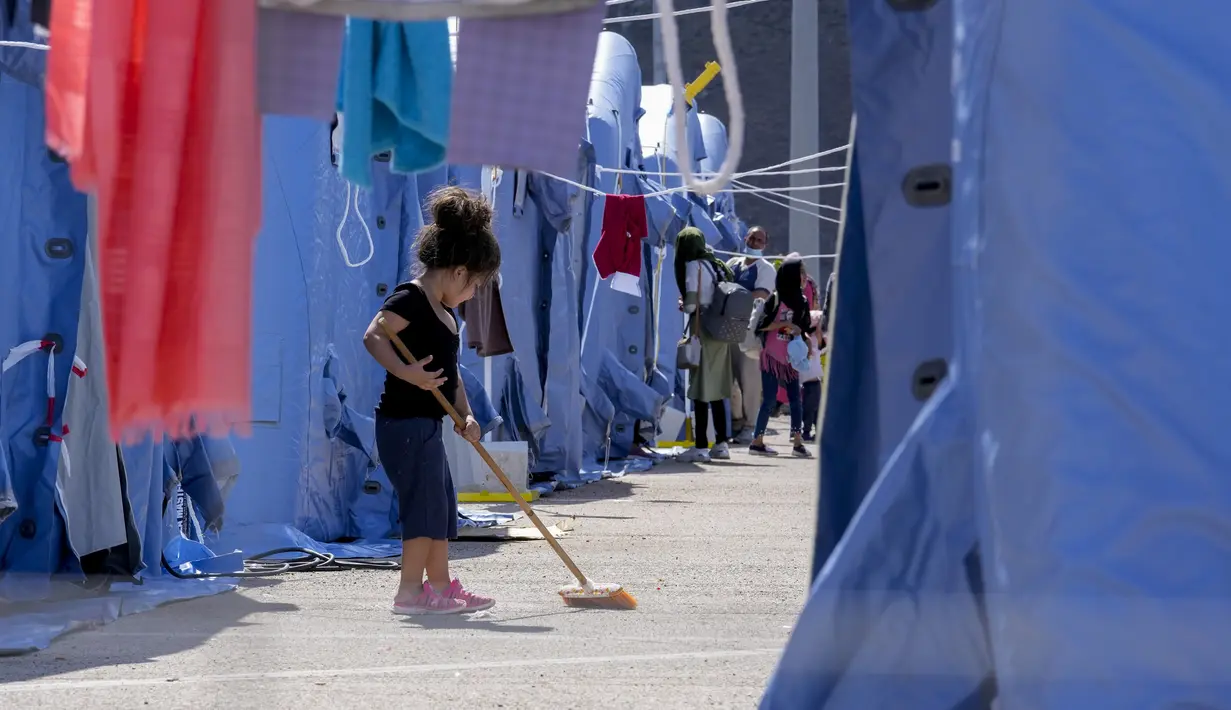 Seorang anak Afghanistan menyapu di kamp pengungsian Palang Merah Italia, Avezzano, Italia, Selasa (31/8/2021). Kamp karantina ini menampung 1.250 imigran. (AP Photo/Andrew Medichini)