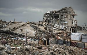 UNRWA menegaskan situasi ini dapat dicegah jika bantuan kemanusiaan tidak terhalang, termasuk dukungan medis dan tempat tinggal layak. Tampak dalam foto, warga Palestina berjalan melewati reruntuhan di tengah cuaca tengah cuaca buruk Kota Gaza, Kamis 11 Desember 2025. (AP Photo/Jehad Alshrafi)