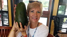 Dalam foto 28 November 2017 memperlihatkan seorang wanita Hawaii, Pamela Wang berpose dengan buah alpukat super jumbo yang ditemukannya di Kealakekua. Pamela menemukan alpukat seberat 2,3 kg yang seukuran dengan kepalanya. (AP Photo/Mary Lou Knurek)
