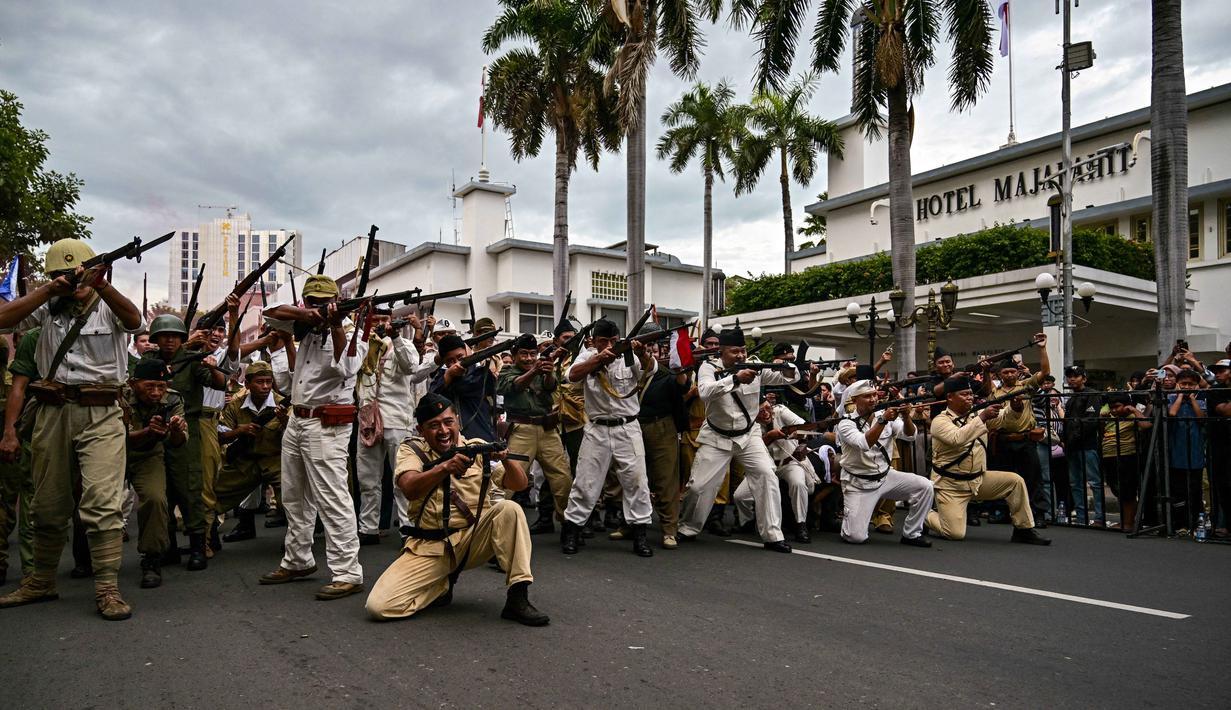 Anggota Komunitas Roode Brug Soerabaia dan Reenactor Indonesia berpartisipasi dalam reka ulang Pertempuran Surabaya, di Surabaya pada Minggu 2 November 2025. Aksi itu memicu baku tembak sengit, dengan efek ledakan dan petasan yang menambah suasana tegang. (Juni KRISWANTO/AFP)