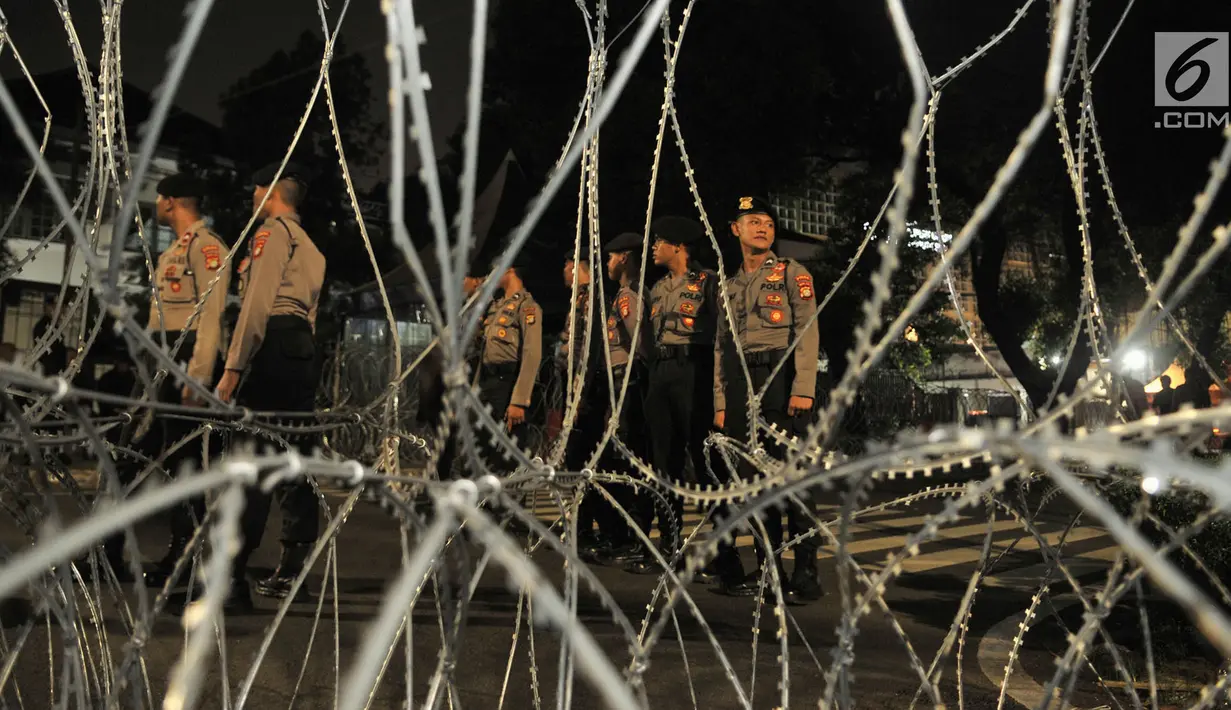 Polisi berdiri di belakang kawat berduri yang telah terpasang di perempatan Jalan Imam Bonjol, Jakarta Pusat, Senin (20/5/2019). Menjelang pengumuman hasil Pemilu 2019 puluhan personel gabungan Polisi dan Brimob juga telah bersiaga di sekitar kantor KPU. (merdeka.com/Iqbal S Nugroho)