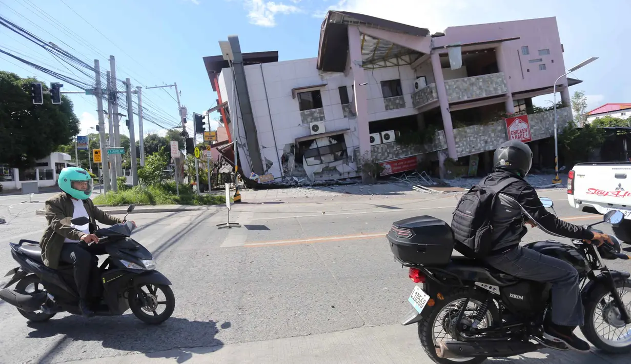 Orang-orang yang mengendarai sepeda motor melewati bangunan yang runtuh setelah gempa bumi di General Santos, Filipina, Senin 8 Juni 2026. (AP Photo)