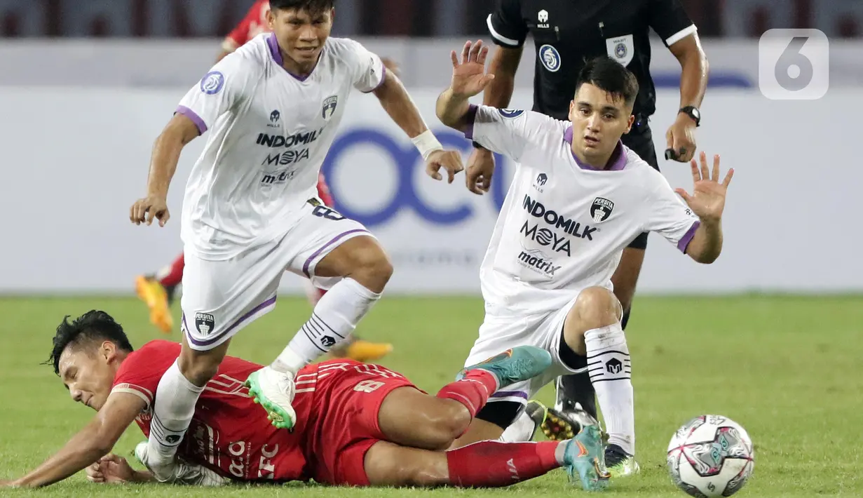 Pemain Persija, Syahrian Abimanyu (bawah) terjatuh saat berebut bola dengan Fahreza Sudin dan Norberto Ezequiel Vidal (Persita) pada lanjutan laga BRI Liga 1 Indonesia 2022-2023 di Stadion Patriot Chandrabhaga, Bekasi, Rabu (24/8/2022). Laga berlangsung sengit dan dimenangkan Persija dengan skor 1-0. (Liputan6.com/Helmi Fithriansyah)